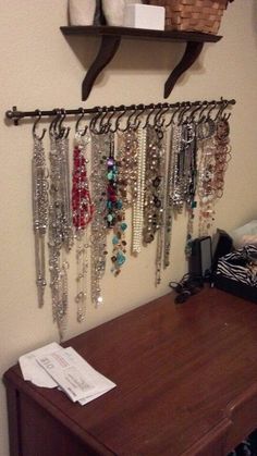 a bunch of necklaces hanging on a wall next to a shelf with other jewelry