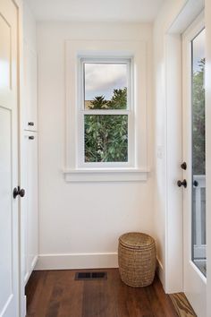 an empty room with a window and basket on the floor