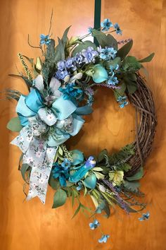 a wreath with blue flowers and green leaves