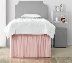 a white bed with pink ruffled bedskirt