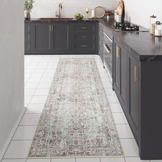 a large rug in the middle of a kitchen with dark cabinets and counter tops on both sides