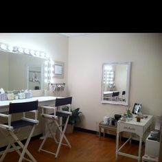 a room with chairs, mirrors and lights on the wall in front of a mirror