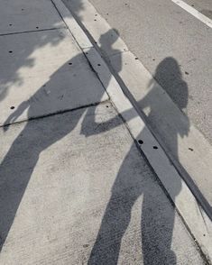 the shadow of two people standing next to each other on a street with a stop sign in the background