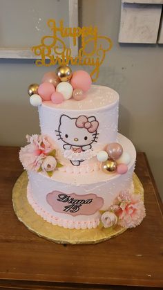 a hello kitty birthday cake with pink and gold decorations on it's tiers