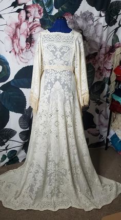 a white wedding dress on display in front of a floral wall