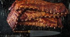 a large piece of meat on top of a cutting board next to a knife