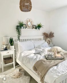 a bedroom with white bedding and plants on the nightstands in front of it