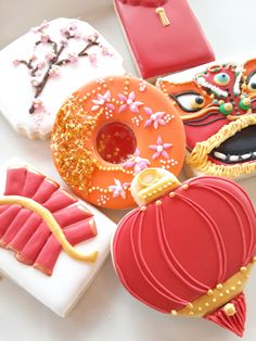 four decorated cookies in the shape of donuts and other treats on a white surface