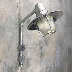 a light that is on the side of a wall next to a cement wall with peeling paint