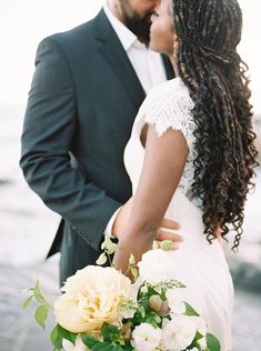 a bride and groom kissing in front of the ocean