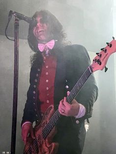 a man in a tuxedo playing an electric guitar at a concert with a microphone