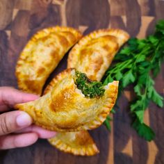 a person holding up some food on top of a wooden cutting board with parsley