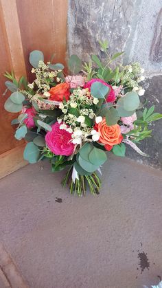 a bouquet of flowers sitting on the ground next to a stone wall and wooden door