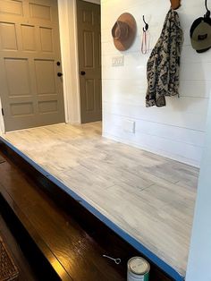 the interior of a house with white walls and wood flooring, two hats hanging on hooks