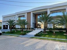 a large white building with palm trees in the front yard and stairs leading up to it