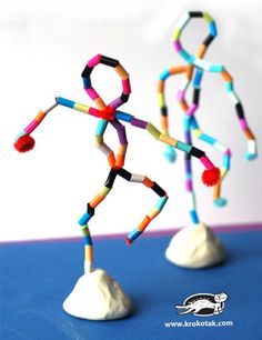 two small plastic figures made out of colored sticks