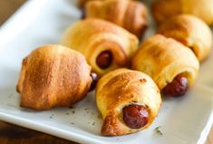 hot dogs wrapped in bread on a white plate