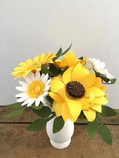 a white vase filled with yellow and white flowers