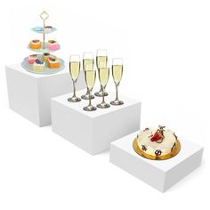 three white pedestals with champagne glasses and cake on them