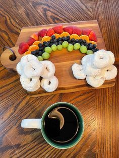 a wooden tray topped with fruit and veggies next to a cup of coffee