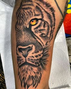 a close up of a tiger's face on a person's leg with yellow eyes