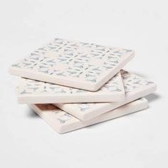 three white and blue patterned coasters stacked on top of each other