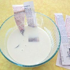 a glass bowl filled with white liquid next to two pieces of paper