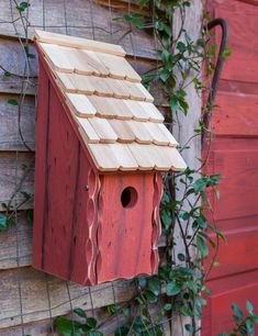 a red birdhouse hanging on the side of a building