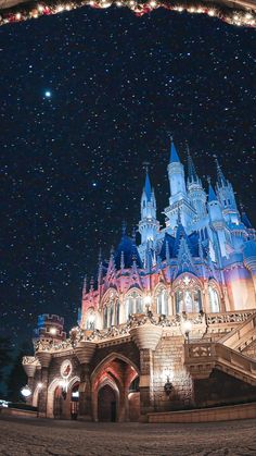 the castle is lit up at night with stars in the sky and lights on it