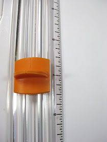 an orange object is on the wall next to a measuring tape and plastic tube holder