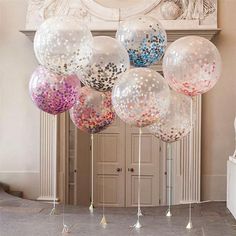 balloons with confetti on them are hanging from the ceiling