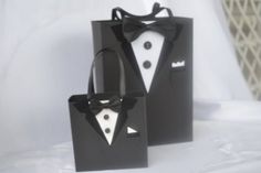 two black paper bags with white tuxedo and bow ties on them, one has a bag in the shape of a suit