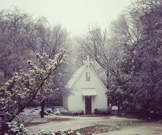 a small white church surrounded by trees and snow