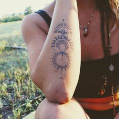 a woman is sitting on the ground with her arm around her neck and tattoos on her body