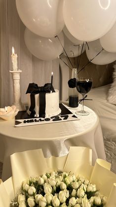 a bunch of white roses sitting on top of a table next to a cake and some balloons