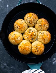 a skillet filled with bread rolls on top of a table next to a white towel