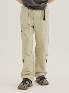 Featuring practical multiple pockets, these are stylish loose cargo pant. They are topped with comfortable banding waist with snap buttons and buckled webbing belt to adjust size easily. - Zip and snap button fastening- Elasticated waistband with webbing belt- Two front slash pockets- Two back patch pockets- Three side cargo pockets- Front tucks- Logo embroidery - Adjustable drawstring at hem- Loose fit Urban Parachute Pants For Outdoor With Belt Loops, Urban Parachute Pants With Belt Loops For Outdoor, Khaki Parachute Pants With Belt Loops For Outdoor Activities, Khaki Parachute Pants With Belt Loops For Outdoor, Utility Parachute Pants With Belt Loops For Outdoor, Outdoor Parachute Pants With Belt Loops And Straight Leg, Khaki Cargo Pants For Outdoor With Belt Loops, Functional Parachute Pants With Belt Loops For Outdoor, Wide Leg Cargo Pants With Belt Loops For Outdoor