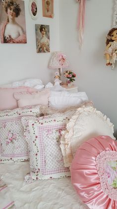 there is a bed with pink and white pillows on the top, and pictures above it