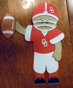 a paper cutout of a football player holding a ball on a wooden table top