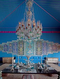 an ornate chandelier hangs from the ceiling in a dining room with blue walls