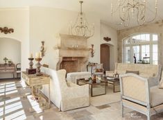 a living room filled with lots of furniture and a chandelier hanging from the ceiling