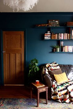 a living room filled with furniture and bookshelves next to a wooden door on a blue wall