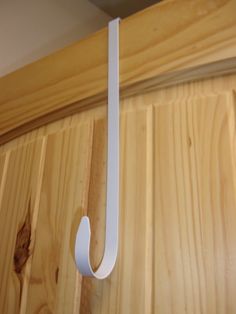 a white hook on the side of a wooden door