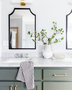 a bathroom with two mirrors and green cabinets