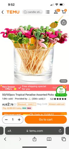 a glass vase filled with fake flowers on top of a table next to a cell phone