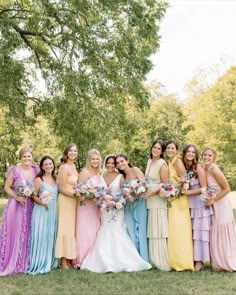 a group of women standing next to each other in long dresses and holding bouquets