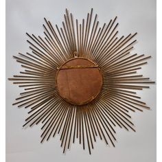 a sunburst shaped mirror hanging on the wall in front of a white background