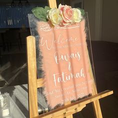 an easel with a welcome sign and flowers on it