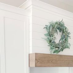 a wreath is hanging on the wall above a fireplace mantel in a white kitchen