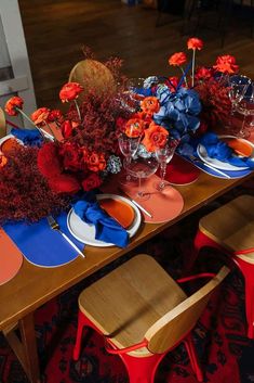 the table is set with red, orange and blue place settings for an elegant dinner